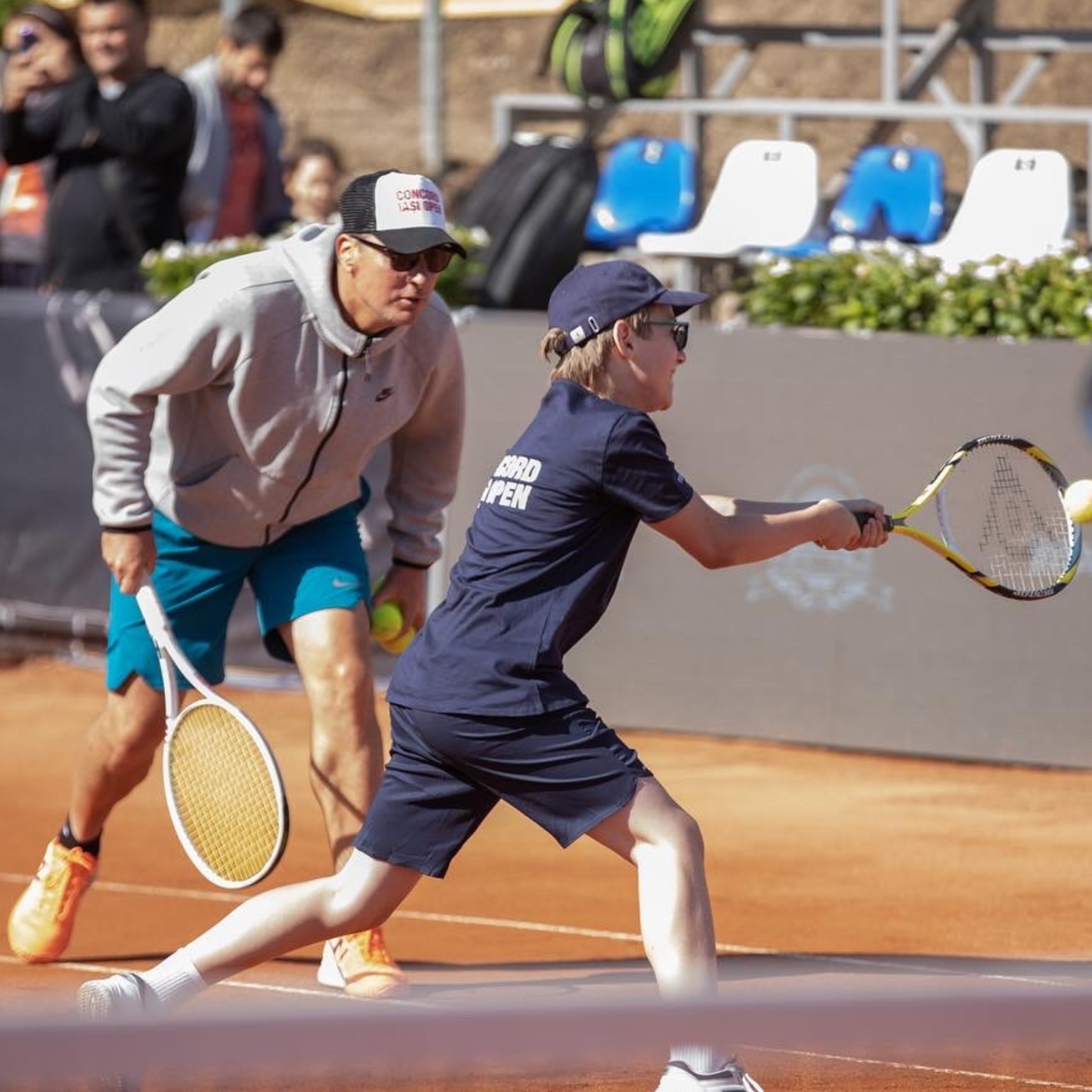 Andrei Pavel, middle-age man, coaching young boy on a tennis clay court.